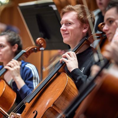 Cellists smile in a rehearsal